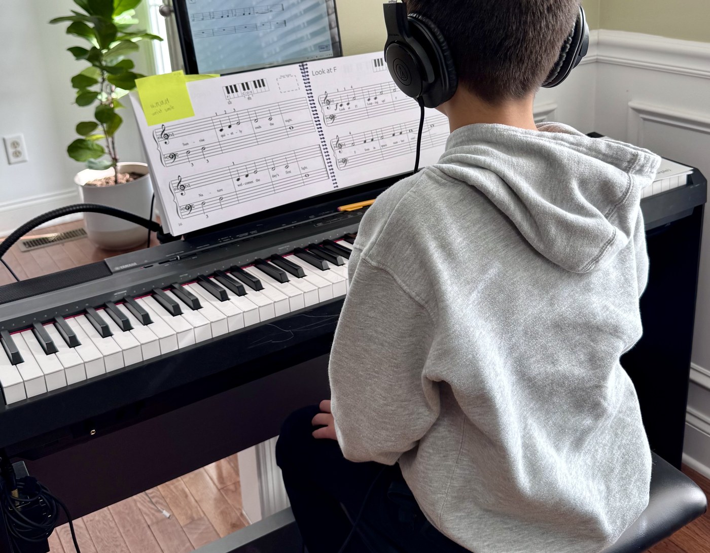 Student reading sheet music at piano